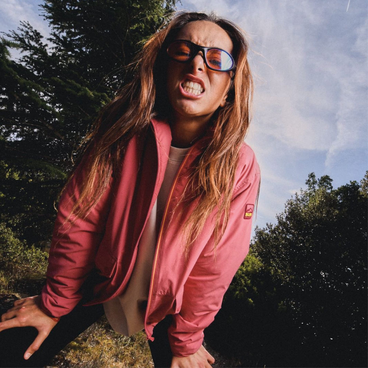 Femme en veste rose Sun Valley et lunettes de soleil, sous un ciel bleu